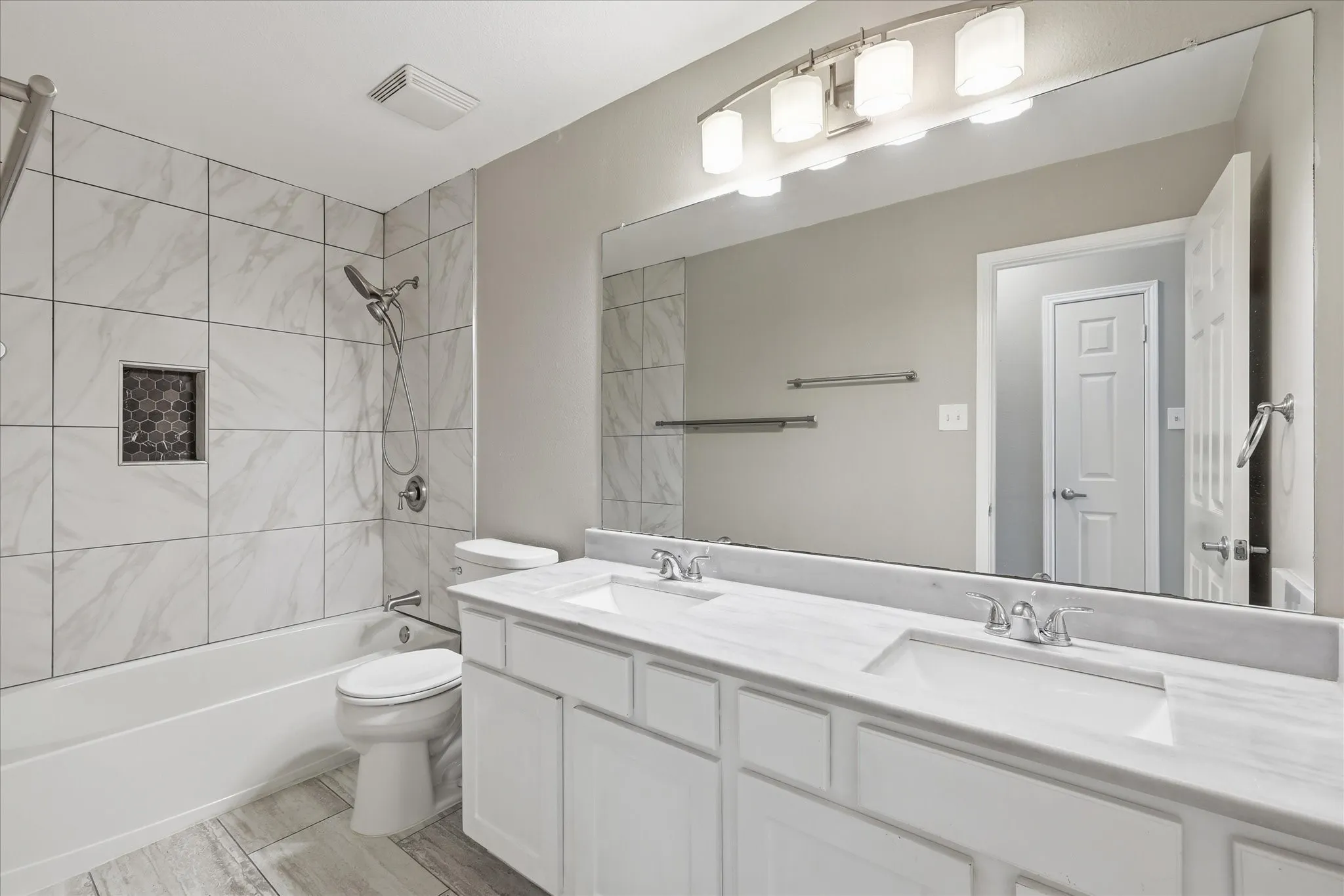 Dual vanity with undermount sinks, stone countertops, and chrome fixtures