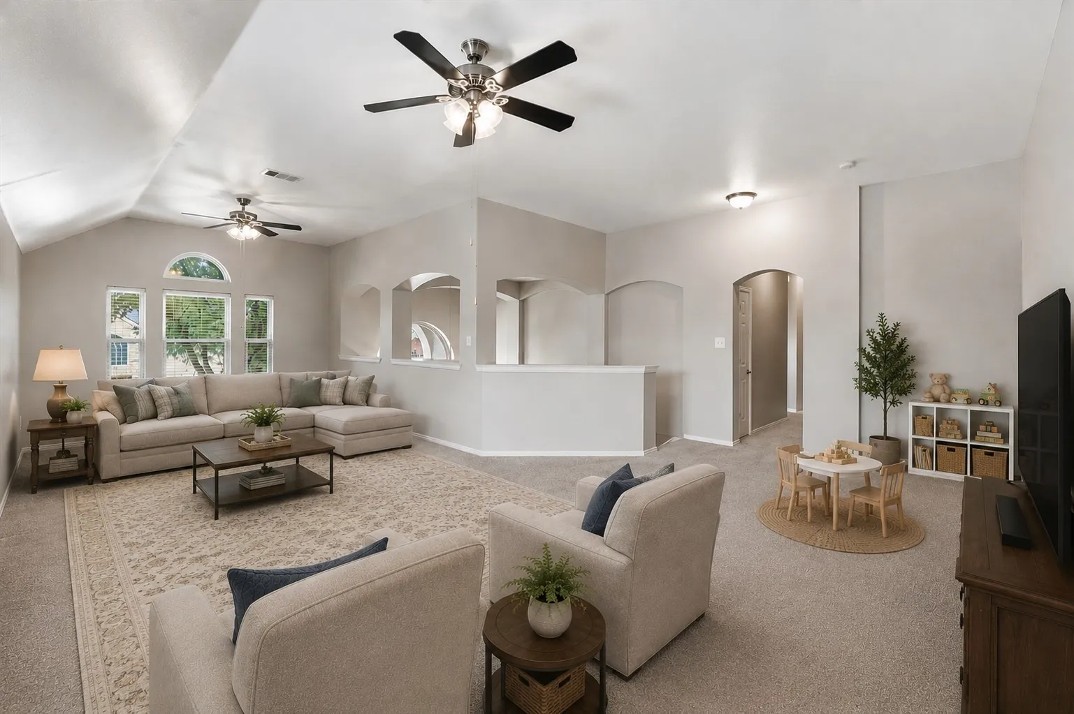 Vaulted ceilings with ceiling fans, arched window, carpeted flooring, and architectural archways