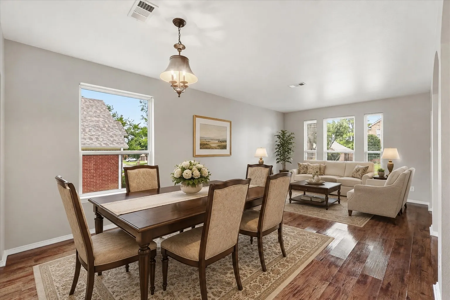 Expansive interior featuring wood-finish flooring, light gray wall paint, multiple windows, and a chandelier lighting fixture