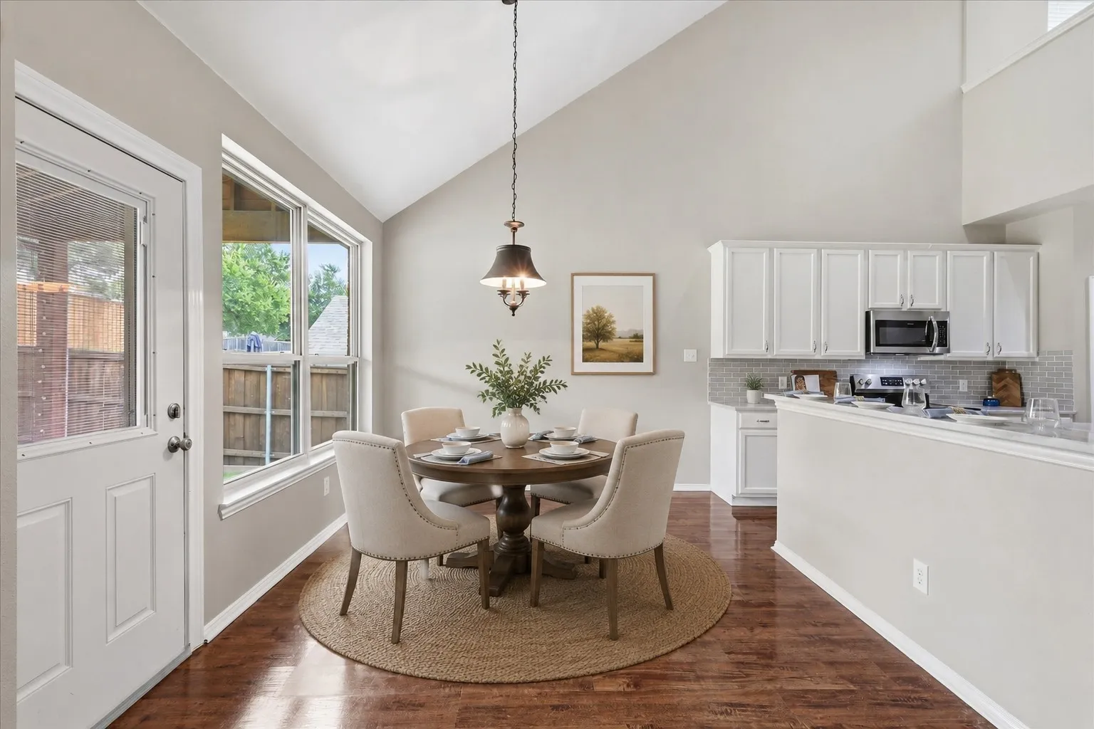 Open-concept dining area with vaulted ceilings, wood-finish flooring, and natural light from expansive windows