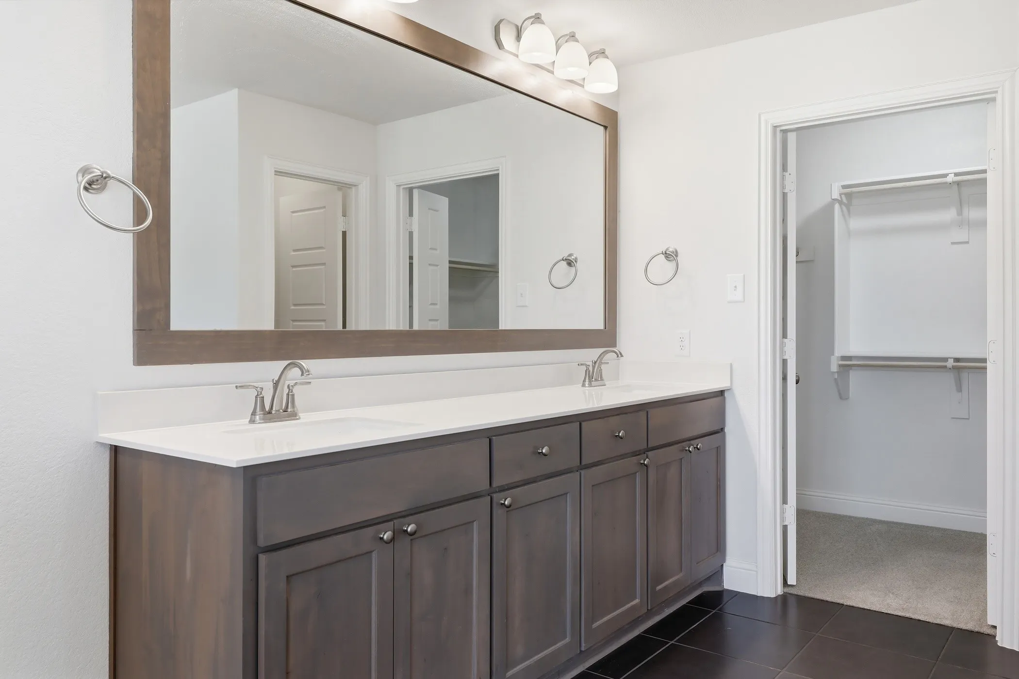 Dual vanity with wood-finish cabinetry, white countertop, and brushed nickel hardware