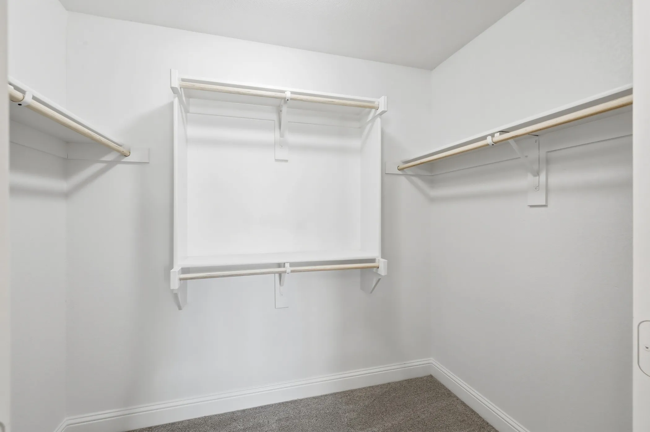 Walk-in closet featuring built-in shelving, multiple hanging rods, and carpet flooring