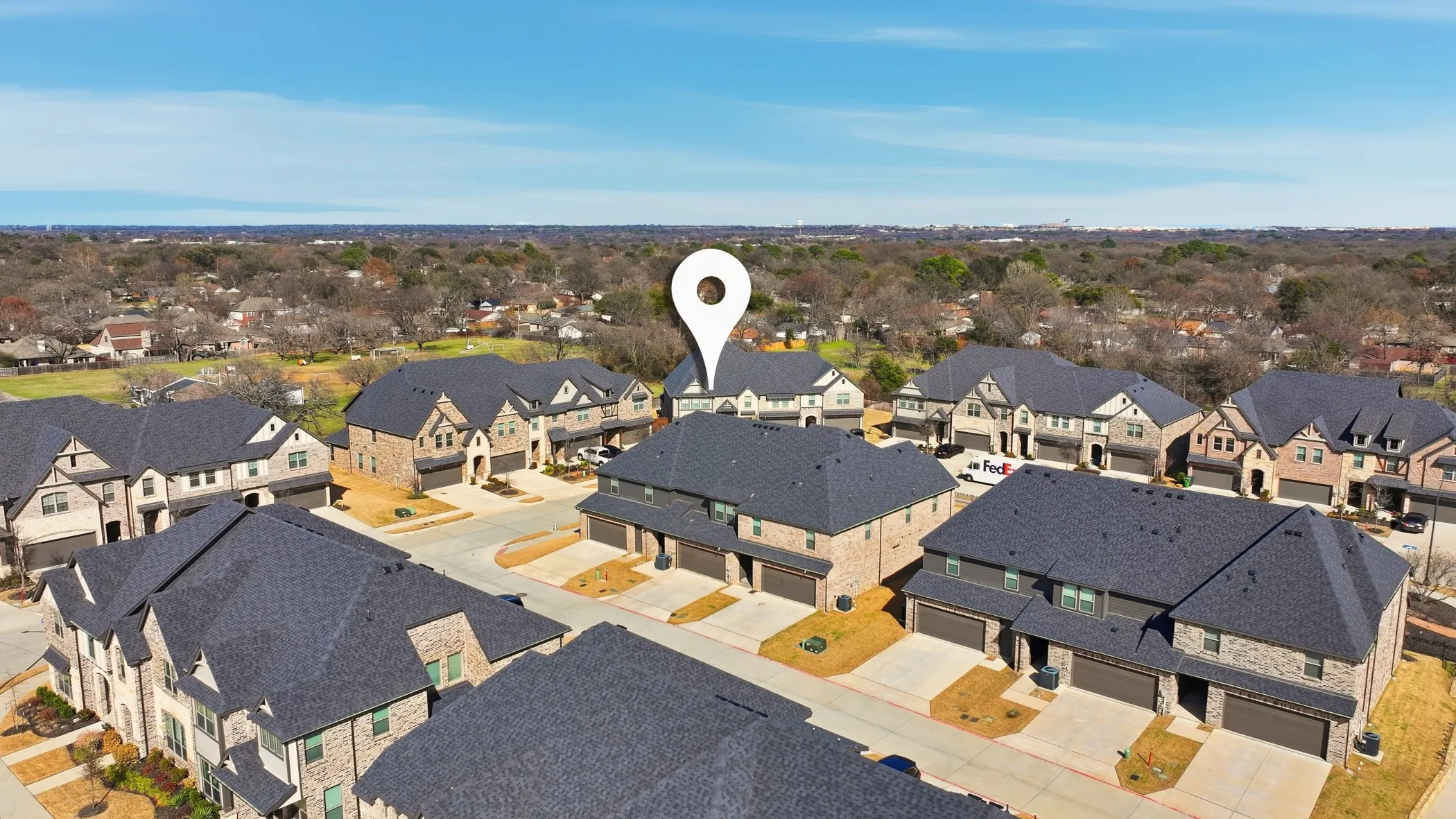 Aerial perspective showcasing a residential development with multiple two-story townhomes, each featuring a private garage