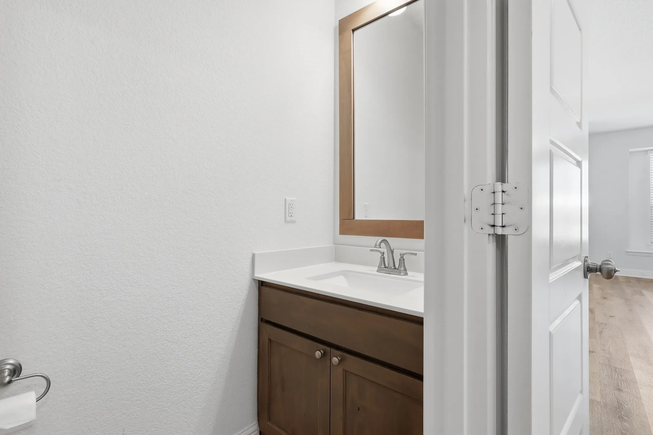 Wood-finish vanity with white countertop, undermount sink, and brushed nickel faucet