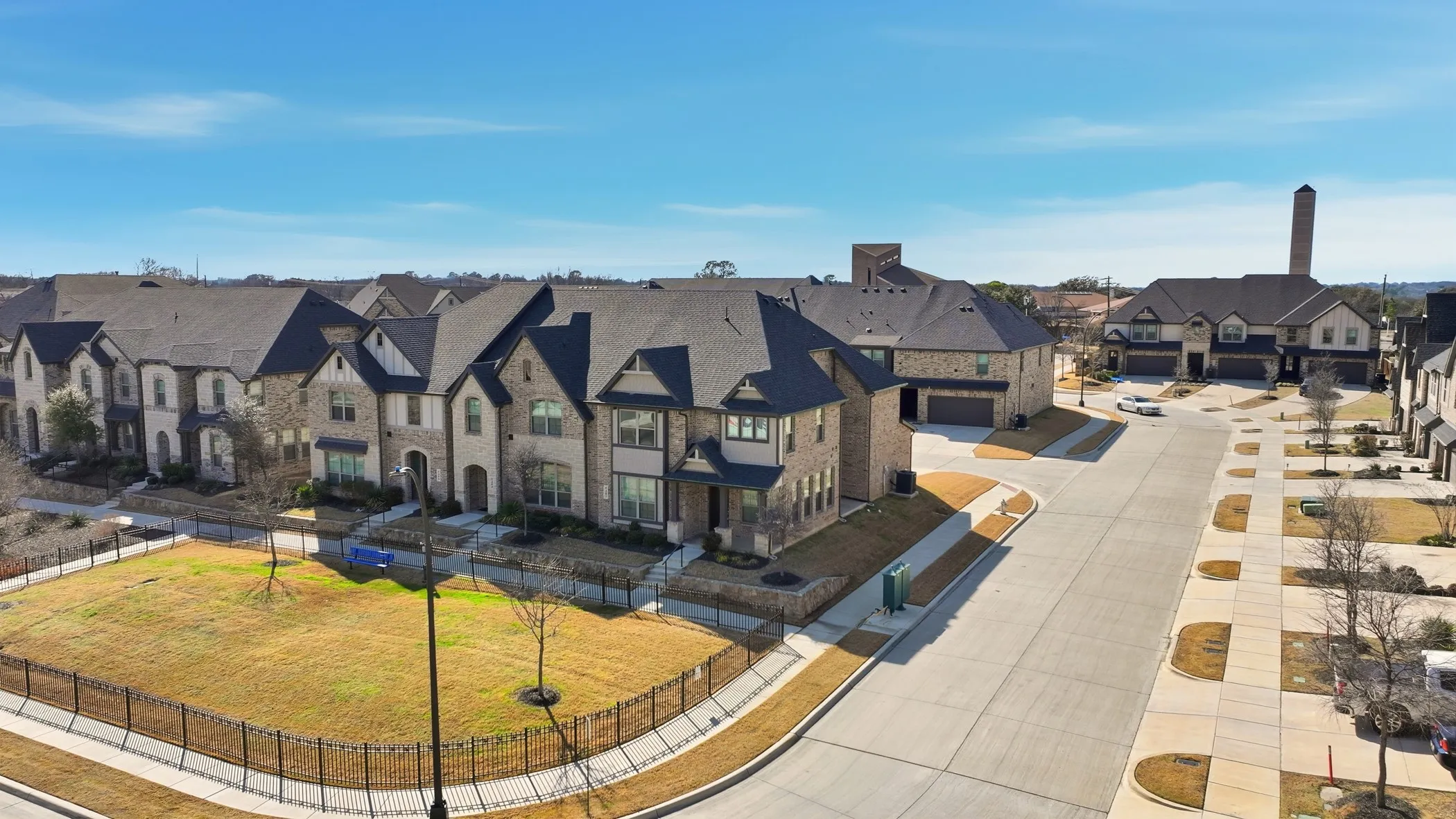 New construction residences with brick and stone exteriors, multiple gables, and attached garages