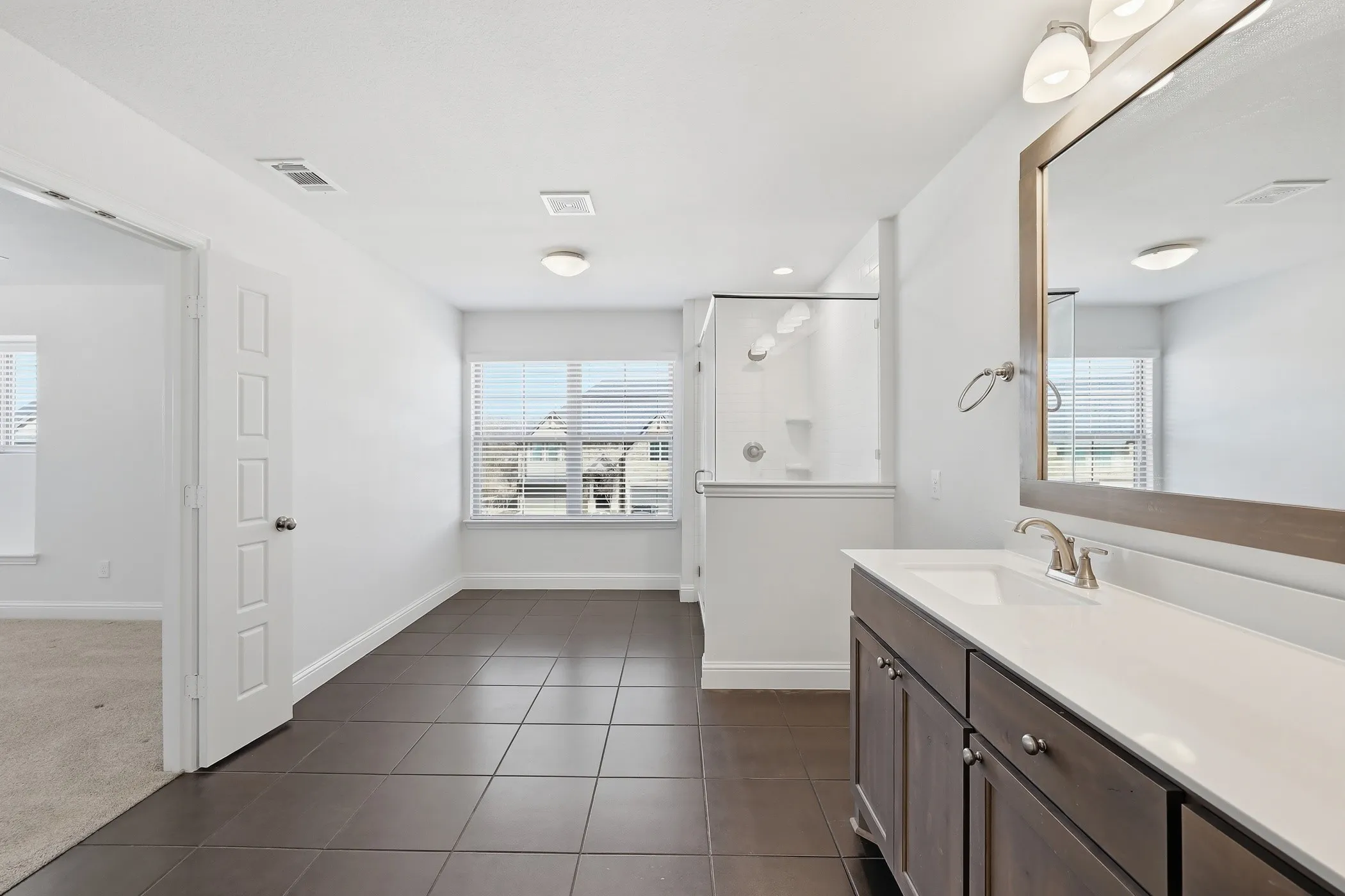 Bathroom featuring a vanity with a white countertop and rectangular sink, a framed mirror, and a glass-enclosed shower