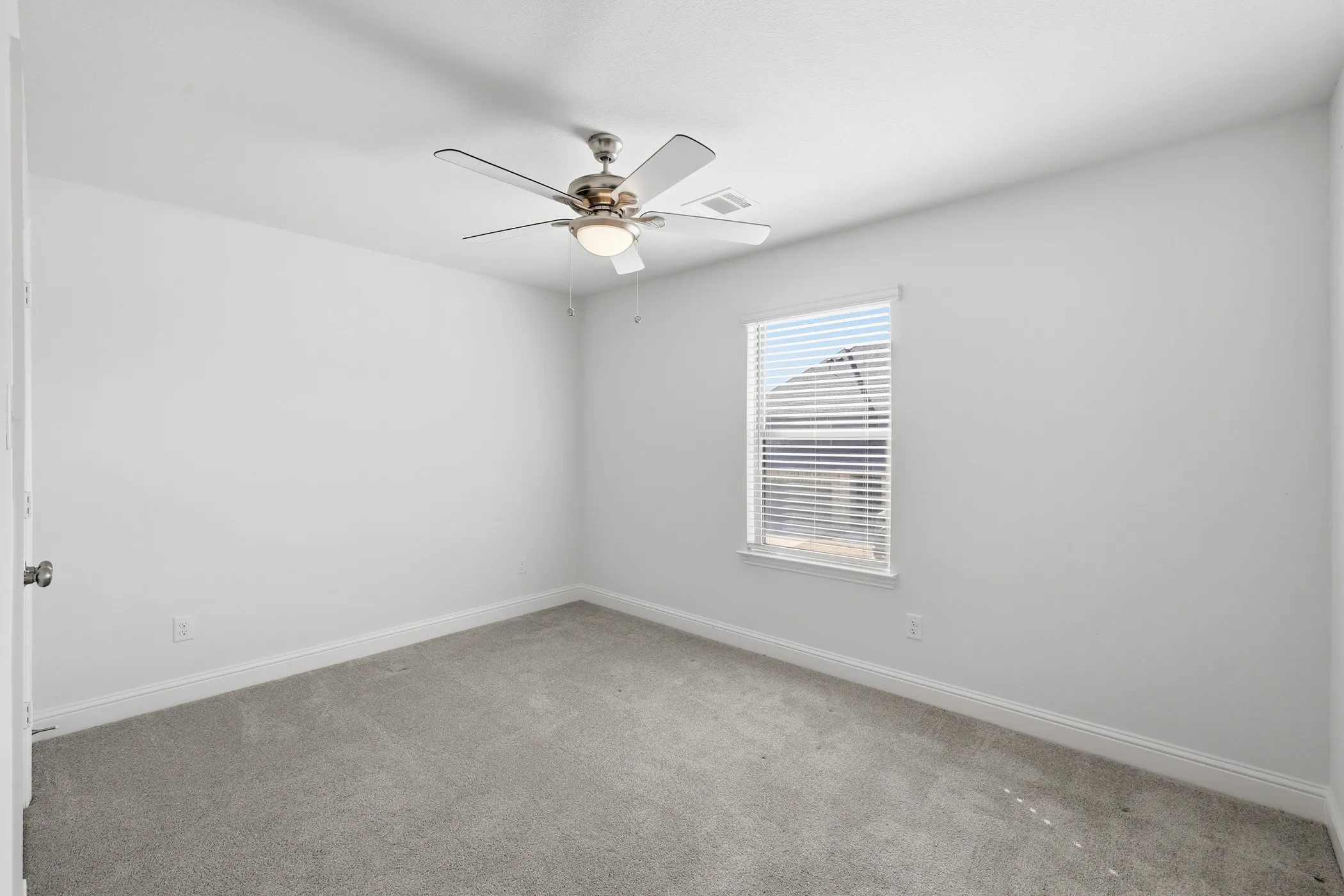 Bright interior with neutral wall finishes, carpet flooring, a single window with blinds, and a ceiling fan with integrated lighting