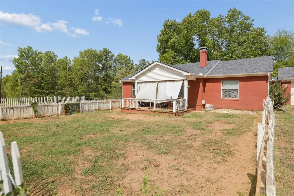 Full exterior view highlighting the property grounds and outbuildings/fencing.