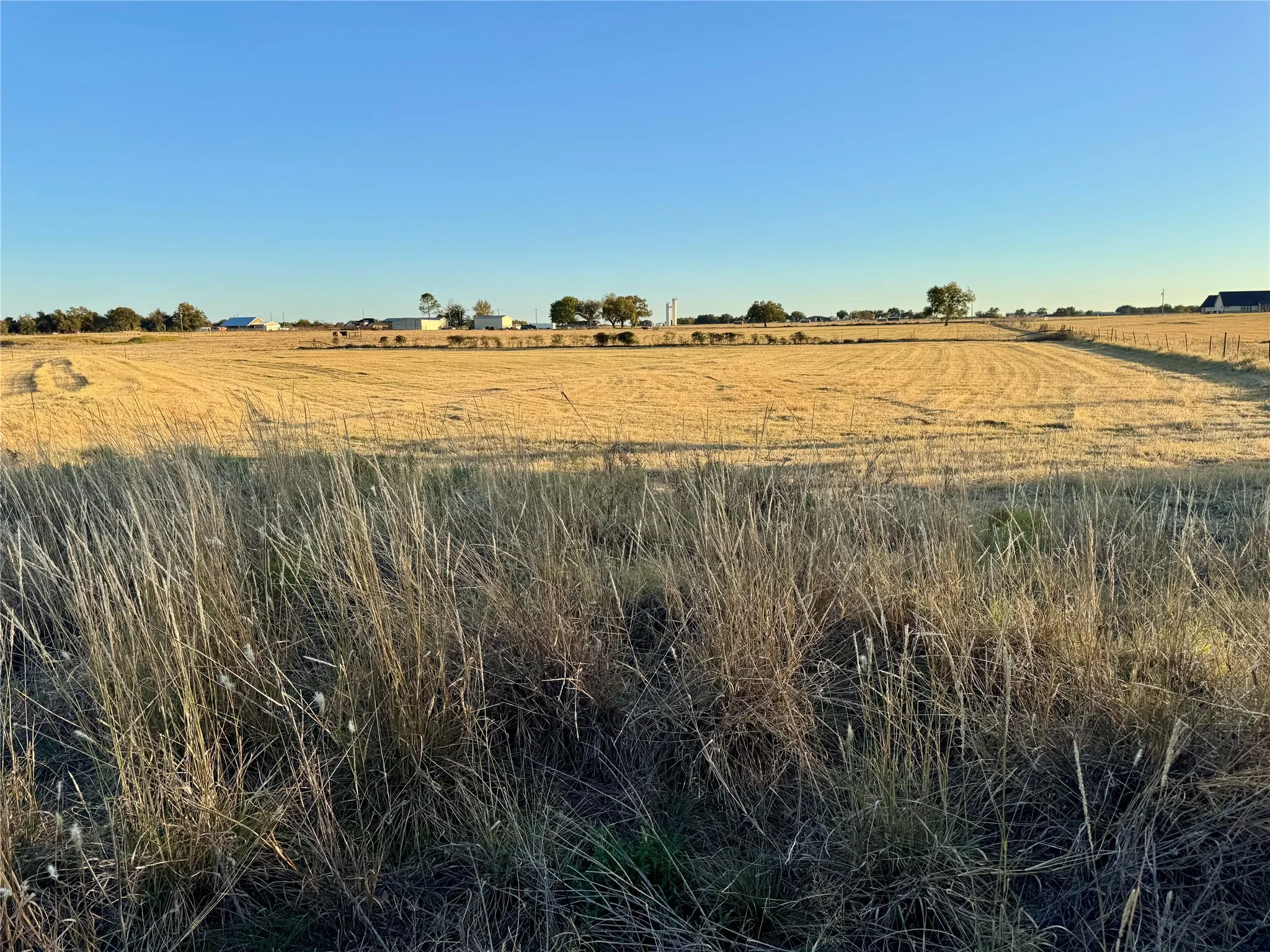 Expansive open land with cultivated fields and distant structures