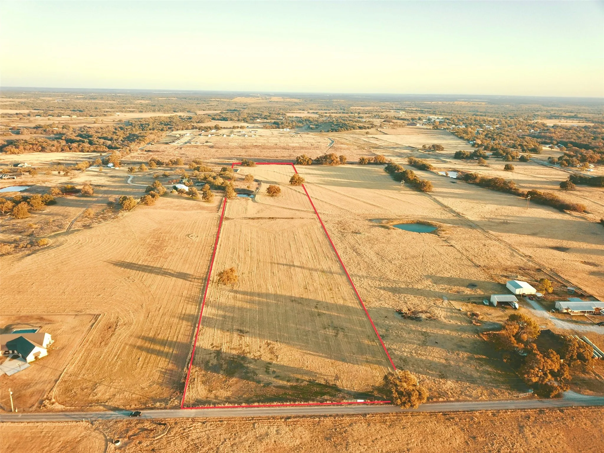 Expansive agricultural land featuring a natural pond and mature trees