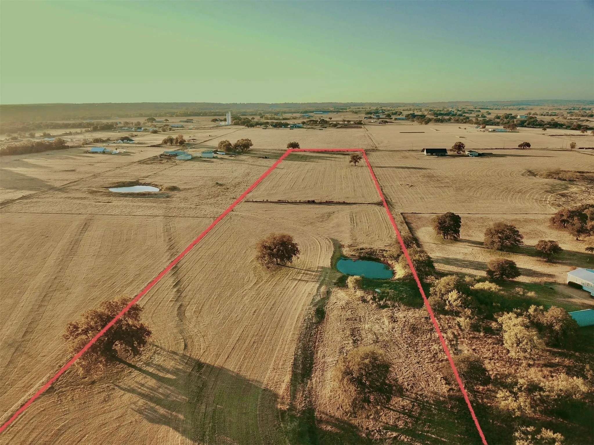 Expansive rural property featuring open fields, scattered mature trees, and two visible ponds