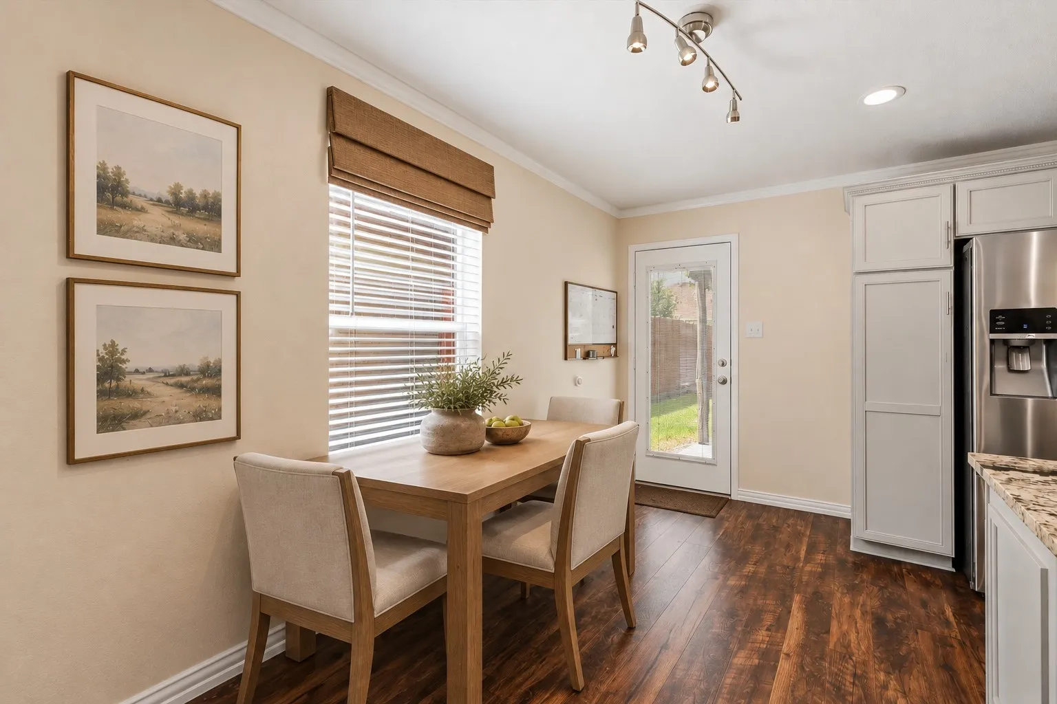 Wood-finish flooring, white cabinetry, stainless steel refrigerator, granite-style countertop, and a glass-paned exterior door