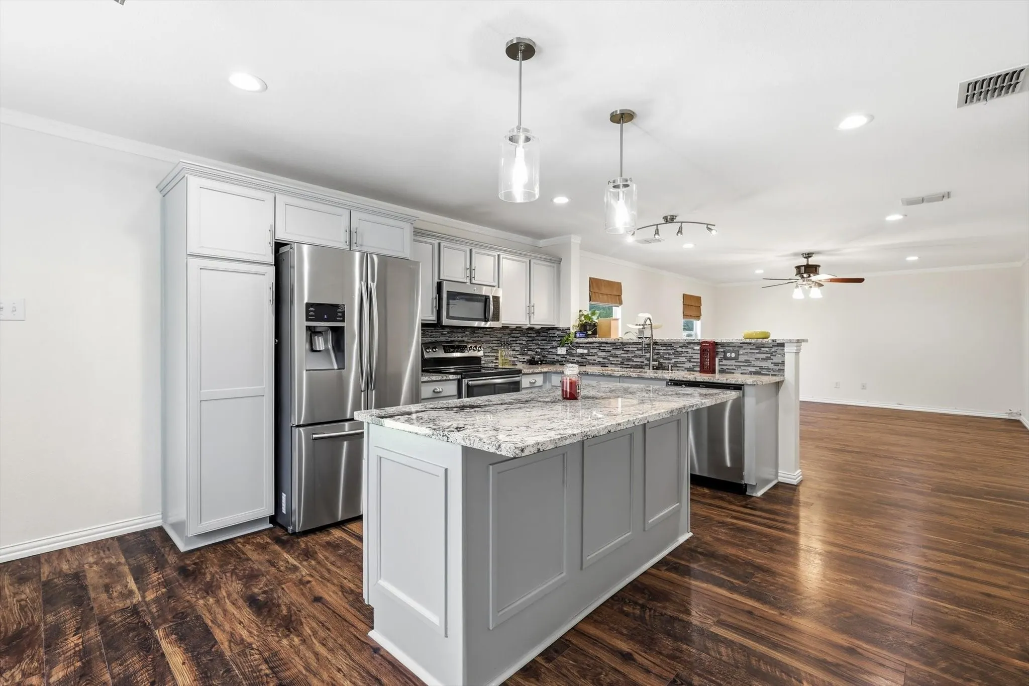Kitchen featuring light gray cabinetry, stainless steel appliances, a center island with a stone countertop, and wood-finish flooring