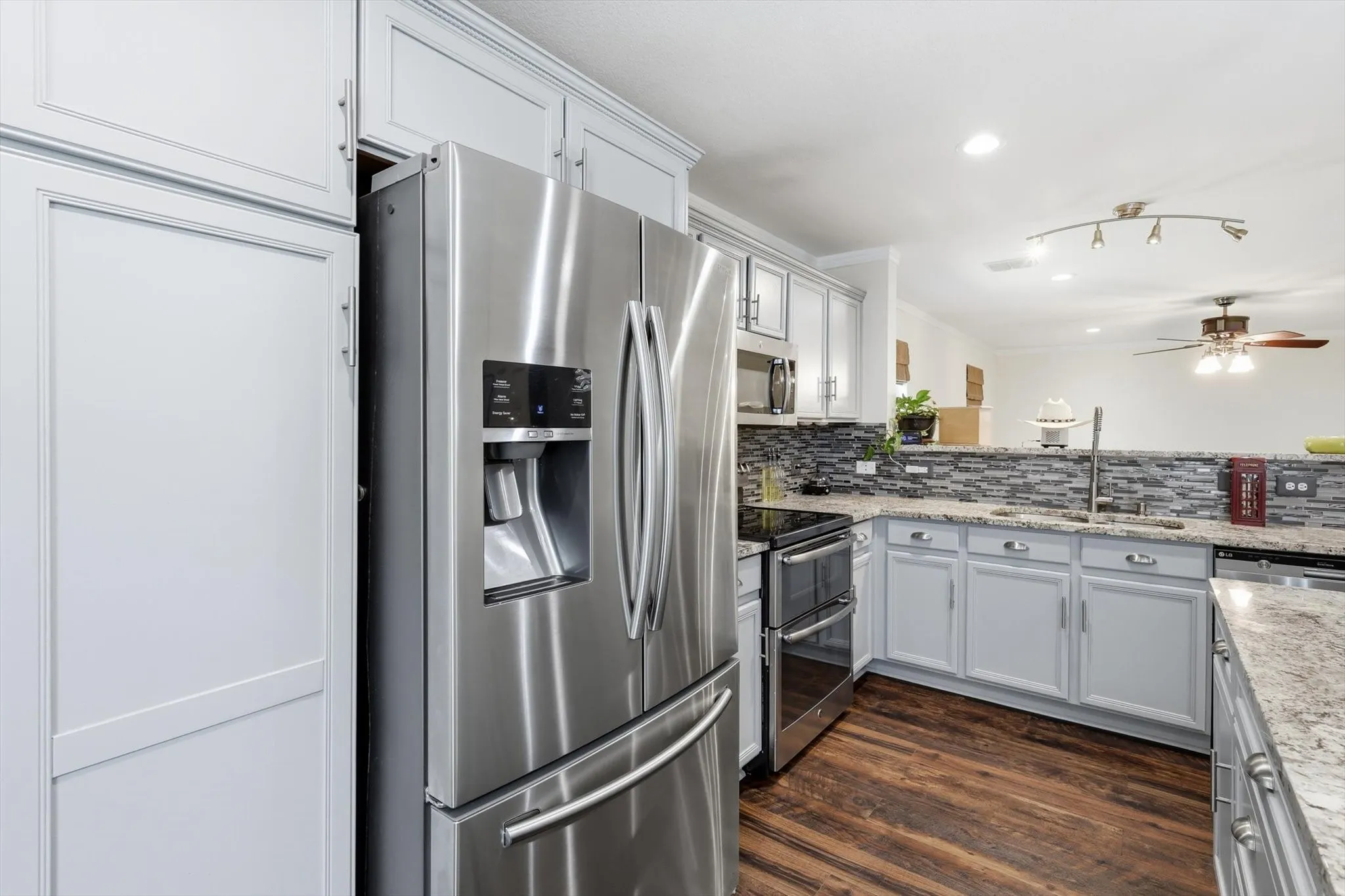 Modern kitchen featuring stainless steel French-door refrigerator with ice and water dispenser, gas range with black glass cooktop, and dual wall ovens