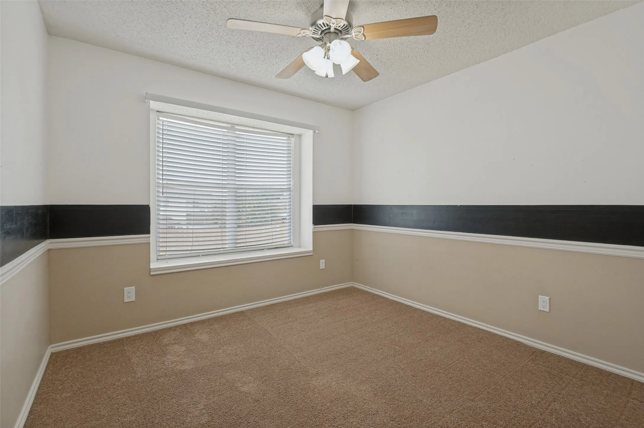 Wall-to-wall carpeting, window with horizontal blinds, two-tone wall treatment, and a ceiling fan with light fixture