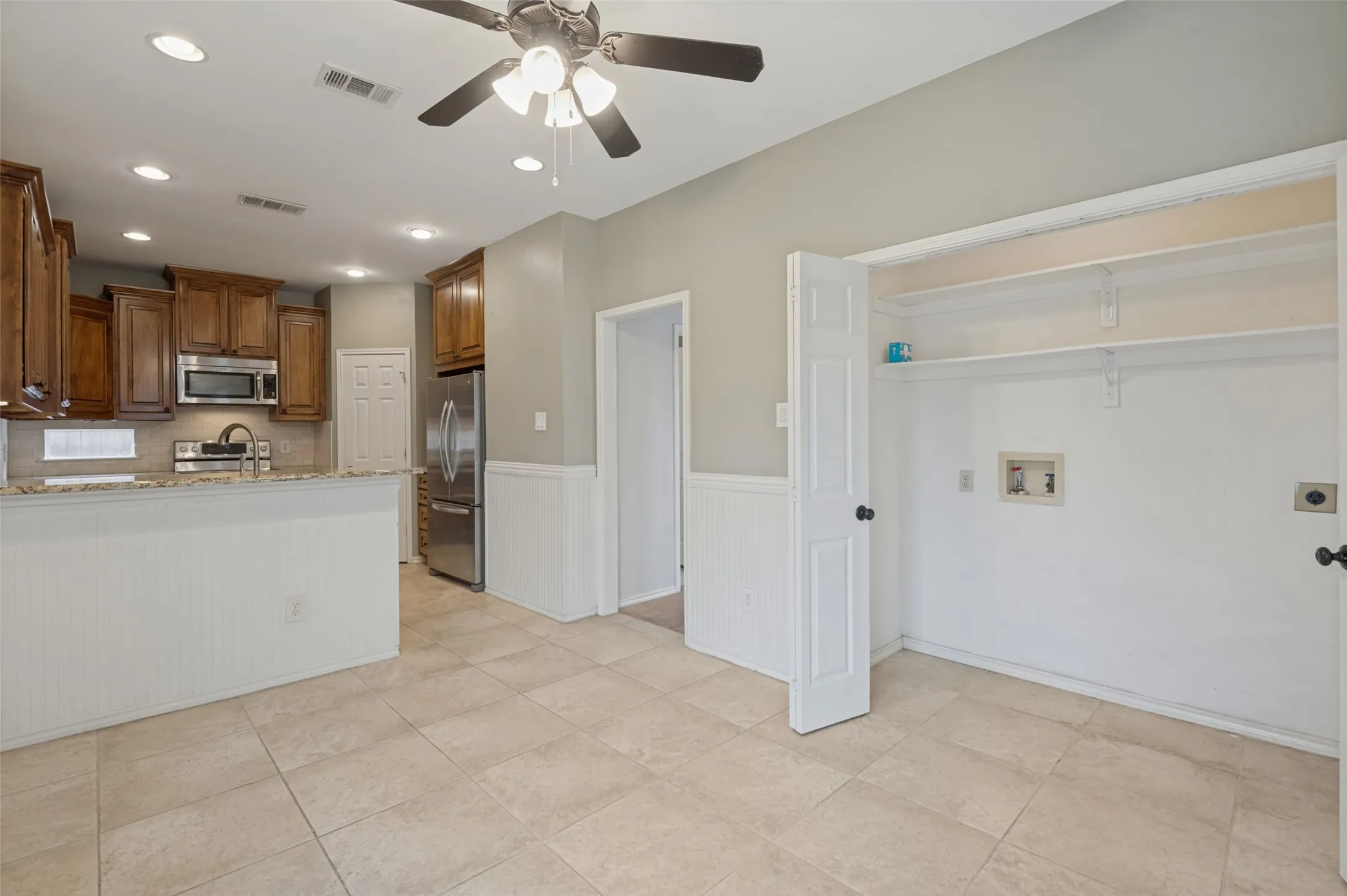 Kitchen features wood cabinetry, stainless steel appliances, and a breakfast bar with a solid surface countertop