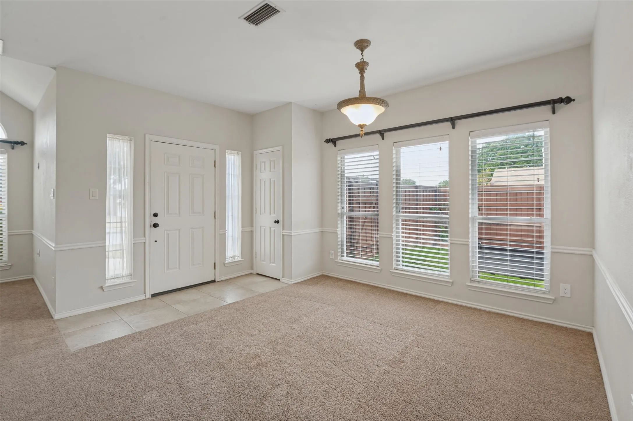 Entryway with tile flooring, wall molding, and a traditional chandelier
