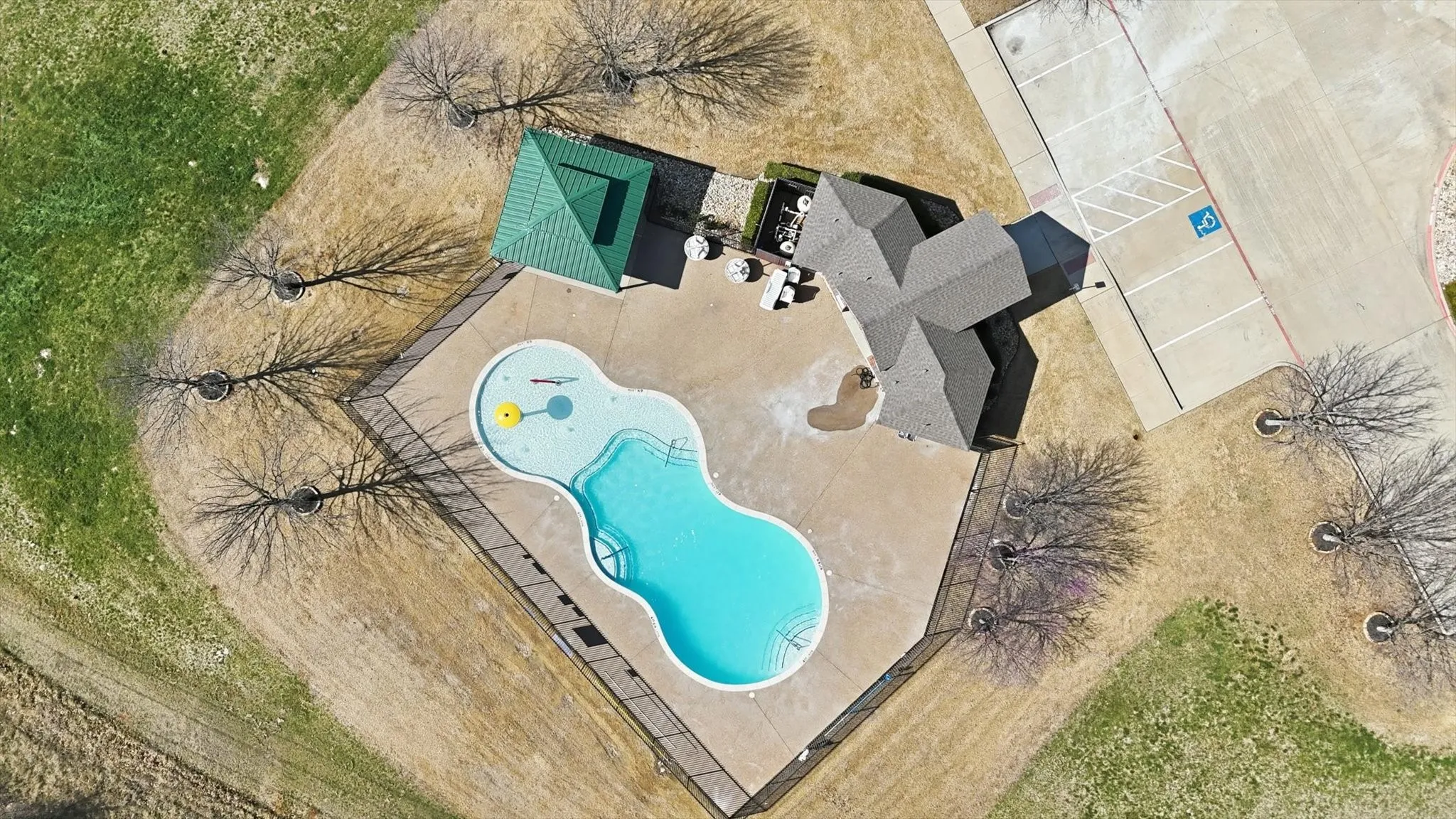 Curvilinear swimming pool with integrated spa, surrounded by a paved patio