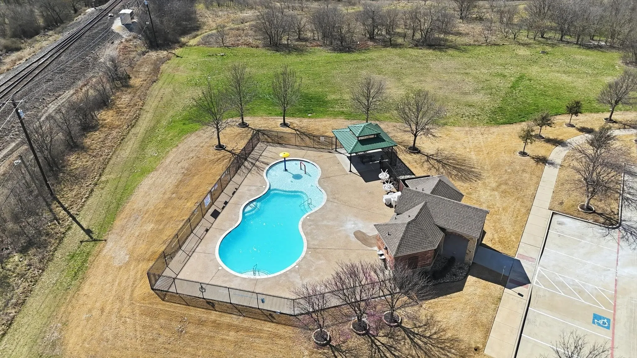 Resort-style pool with surrounding concrete decking, shaded gazebo, and a clubhouse building