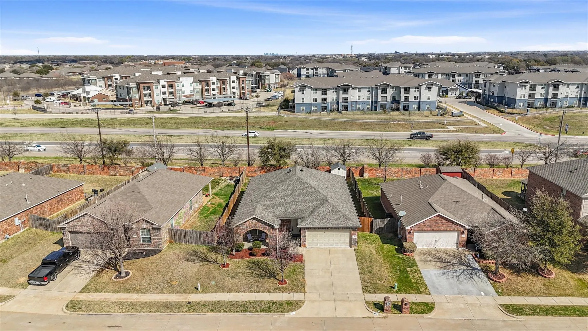 Brick exterior with an attached garage, paved driveway, and a fenced backyard