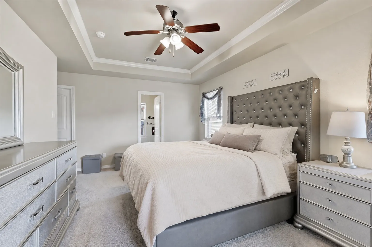 Tray ceiling with crown molding, ceiling fan with integrated lighting, carpeted flooring, and a paneled interior door