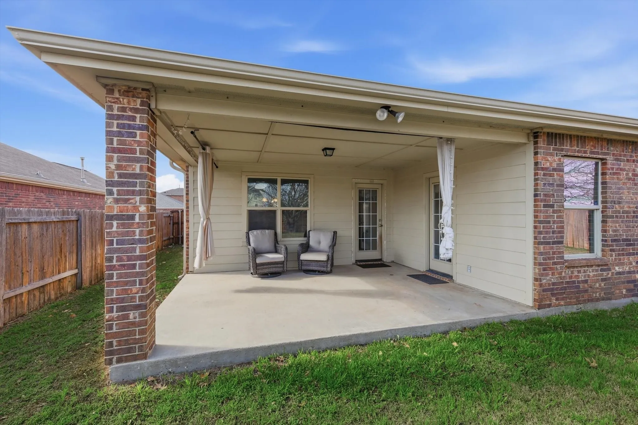 Covered concrete patio featuring brick columns, recessed lighting, and dual exterior doors