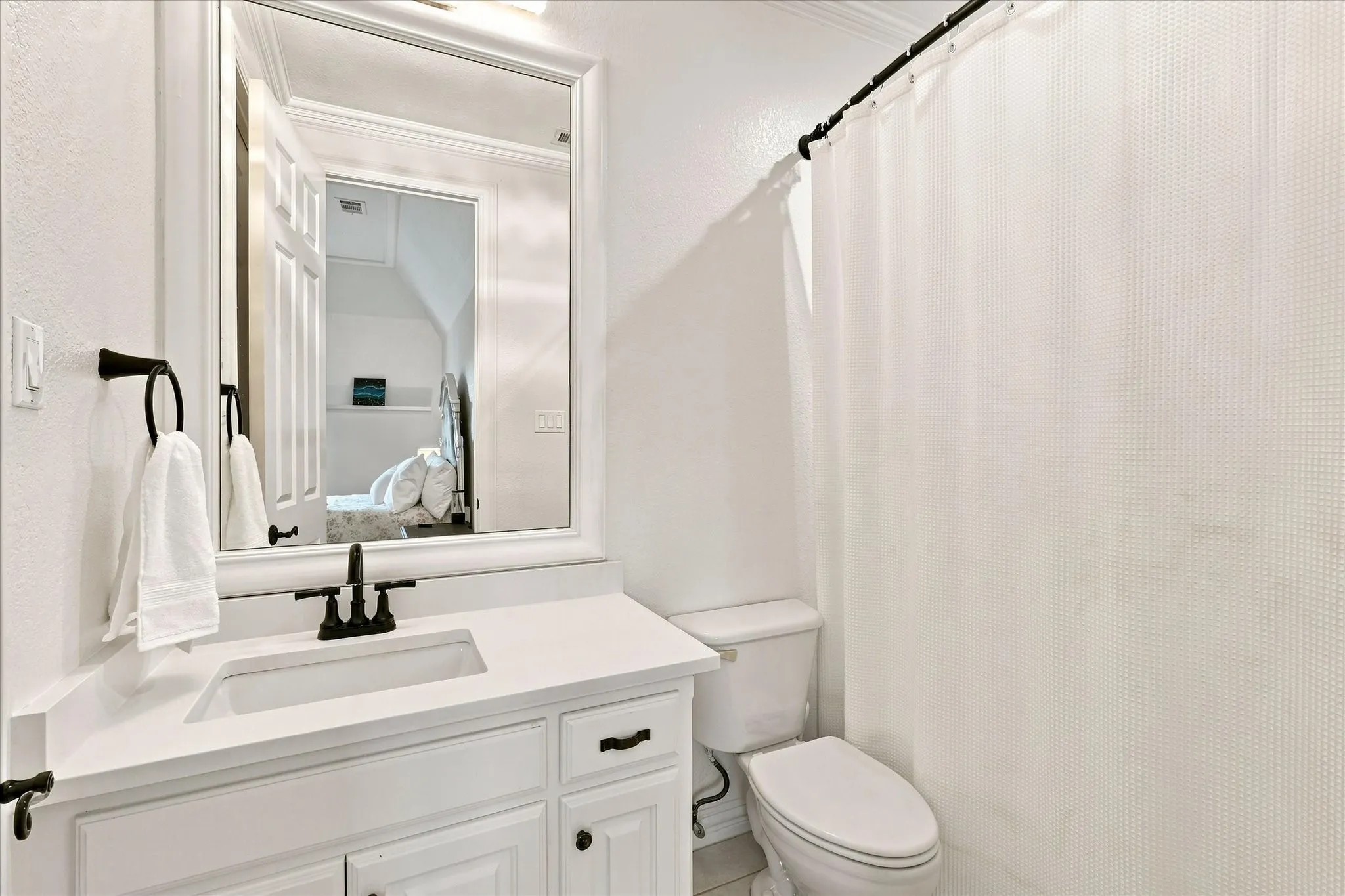 White vanity with integrated sink, matte black faucet, and framed mirror