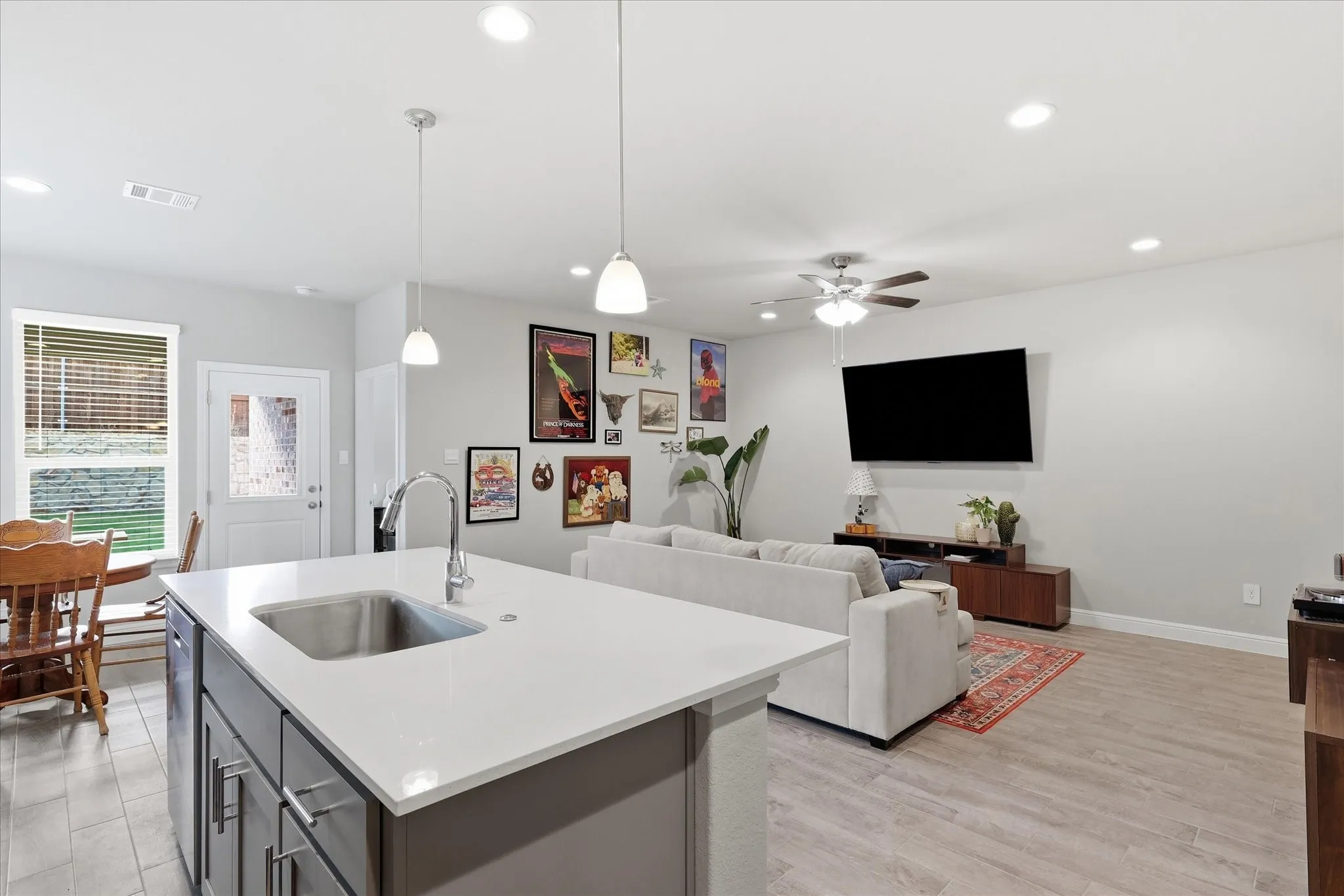 Kitchen island with an undermount sink, quartz countertop, and pendant lighting