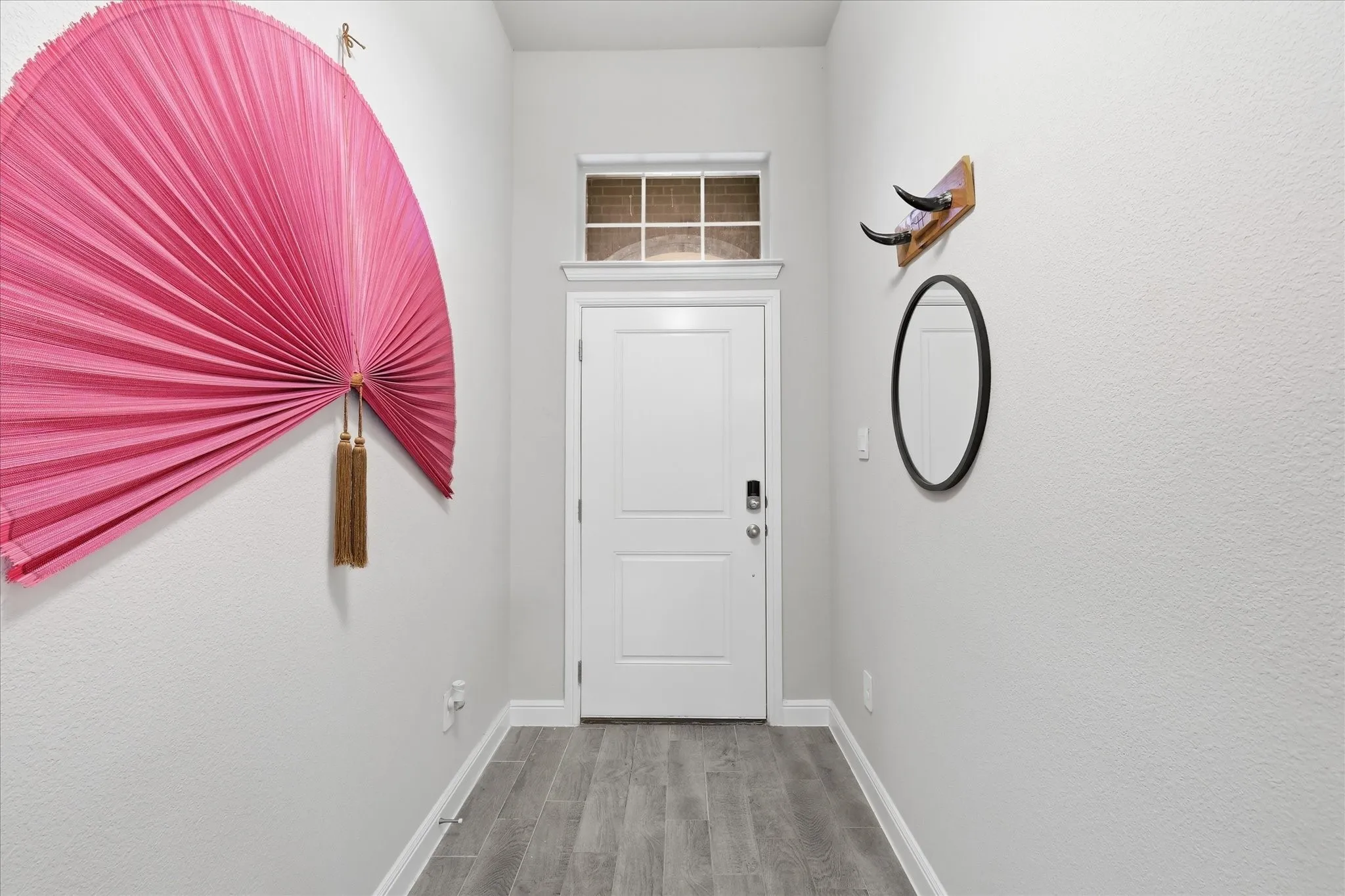 Entryway featuring a paneled door with a transom window, wood-finish flooring, and crisp white trim