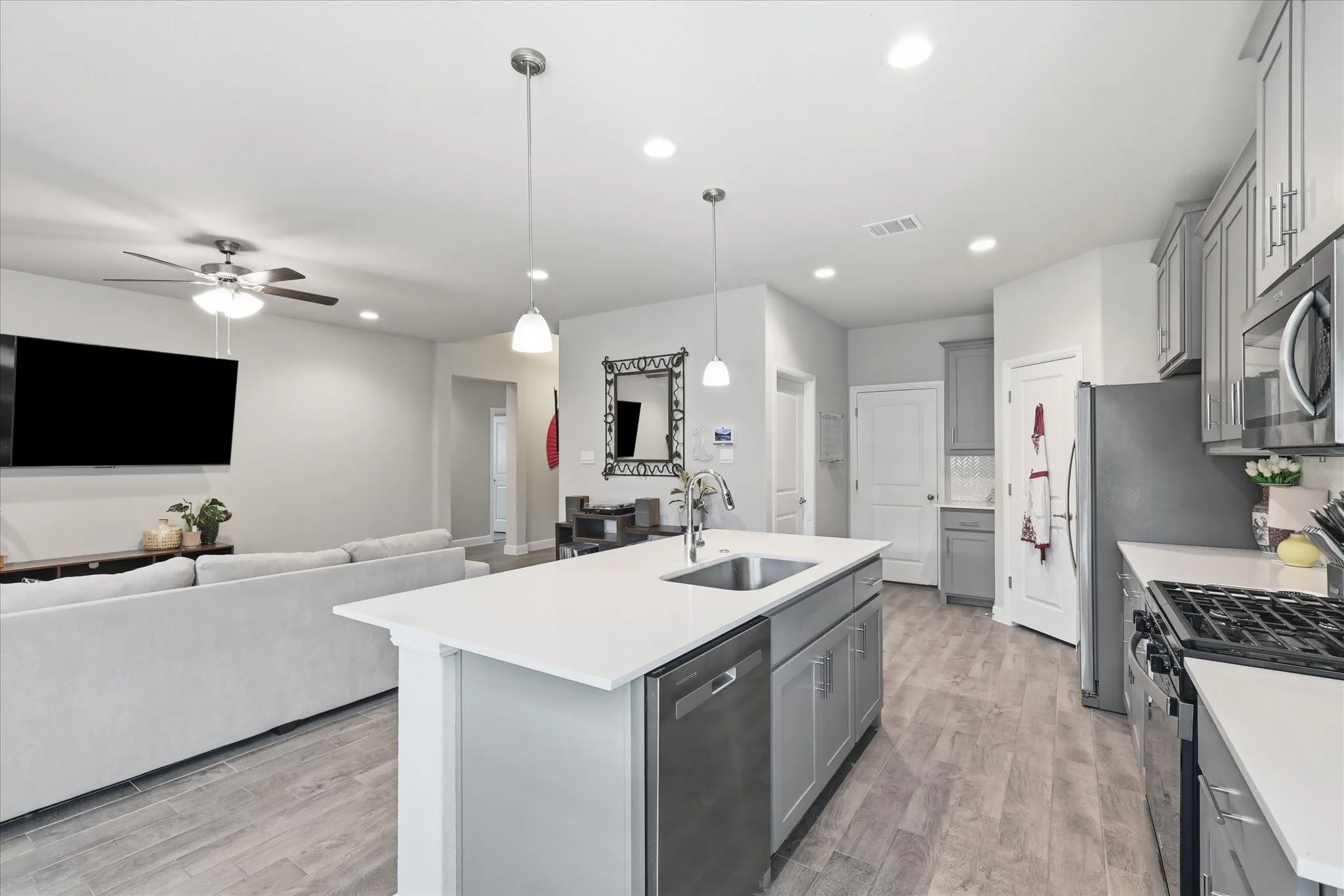 Kitchen featuring a center island with sink, stainless steel appliances, and grey cabinetry