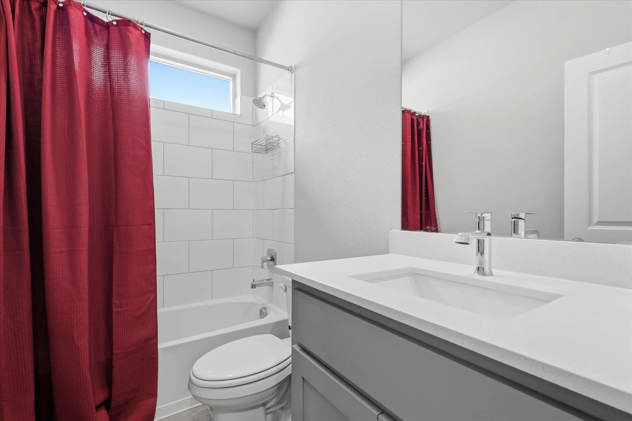 Tub-shower combination with subway tile surround, sleek vanity with integrated sink, chrome fixtures, and a transom window
