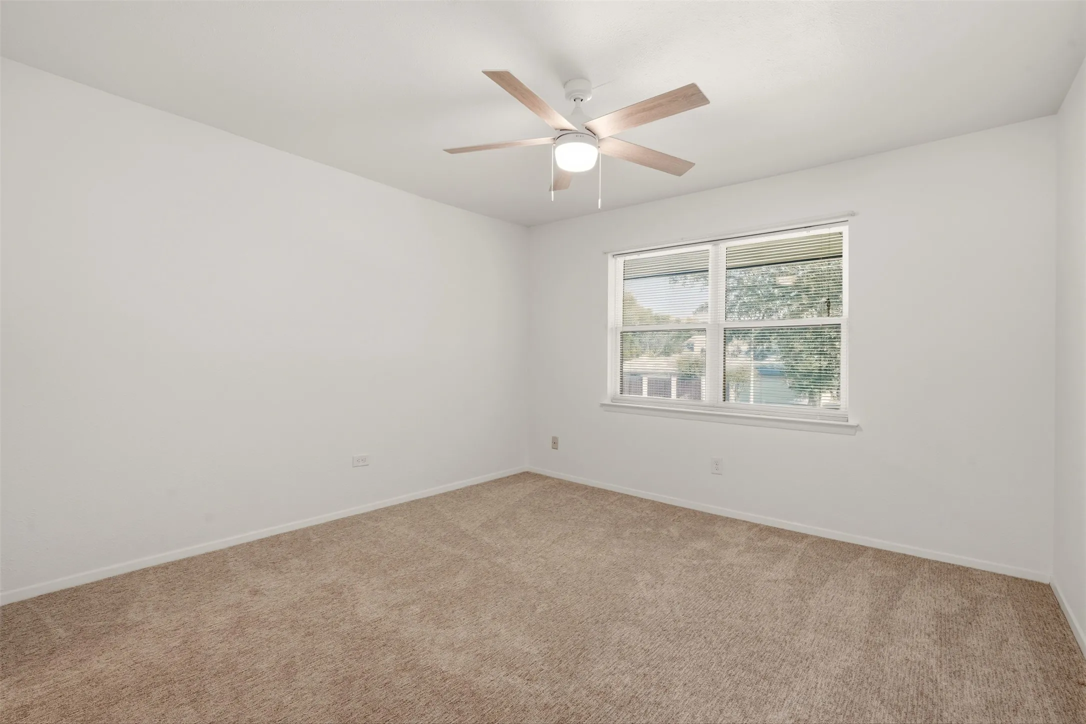 Bright corner bedroom with abundant natural light from dual windows, neutral wall finishes, and ceiling fan with integrated lighting