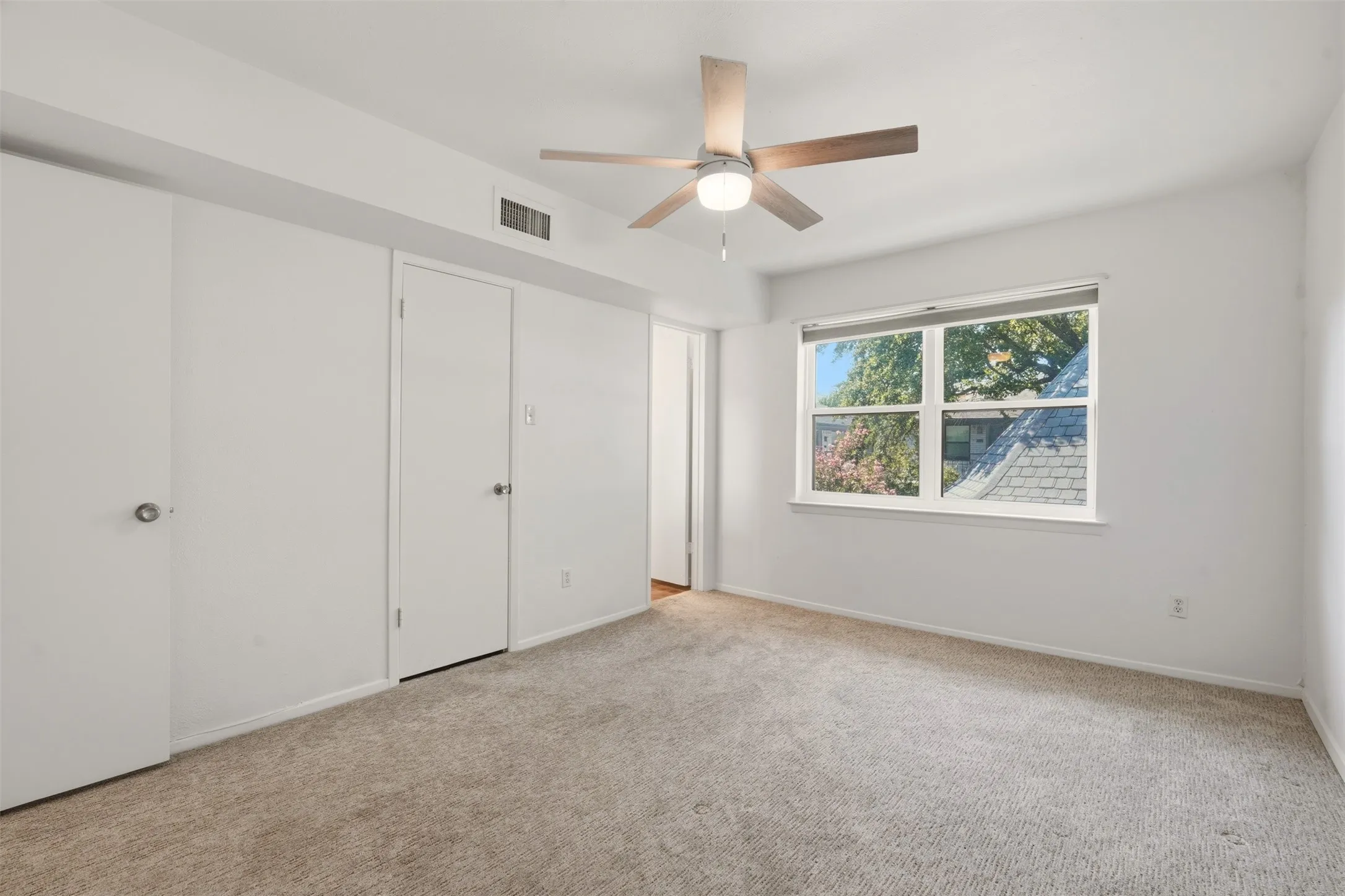 Neutral-toned carpeting, white walls, and a multi-pane window