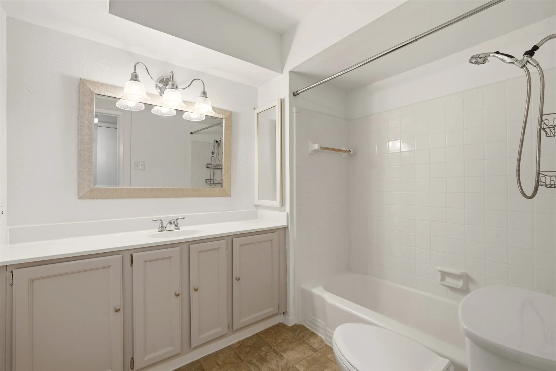 Spa-inspired primary bathroom featuring a dual-sink vanity with ample storage, framed mirror with integrated lighting, and a spacious walk-in shower with glass enclosure and rainfall showerhead