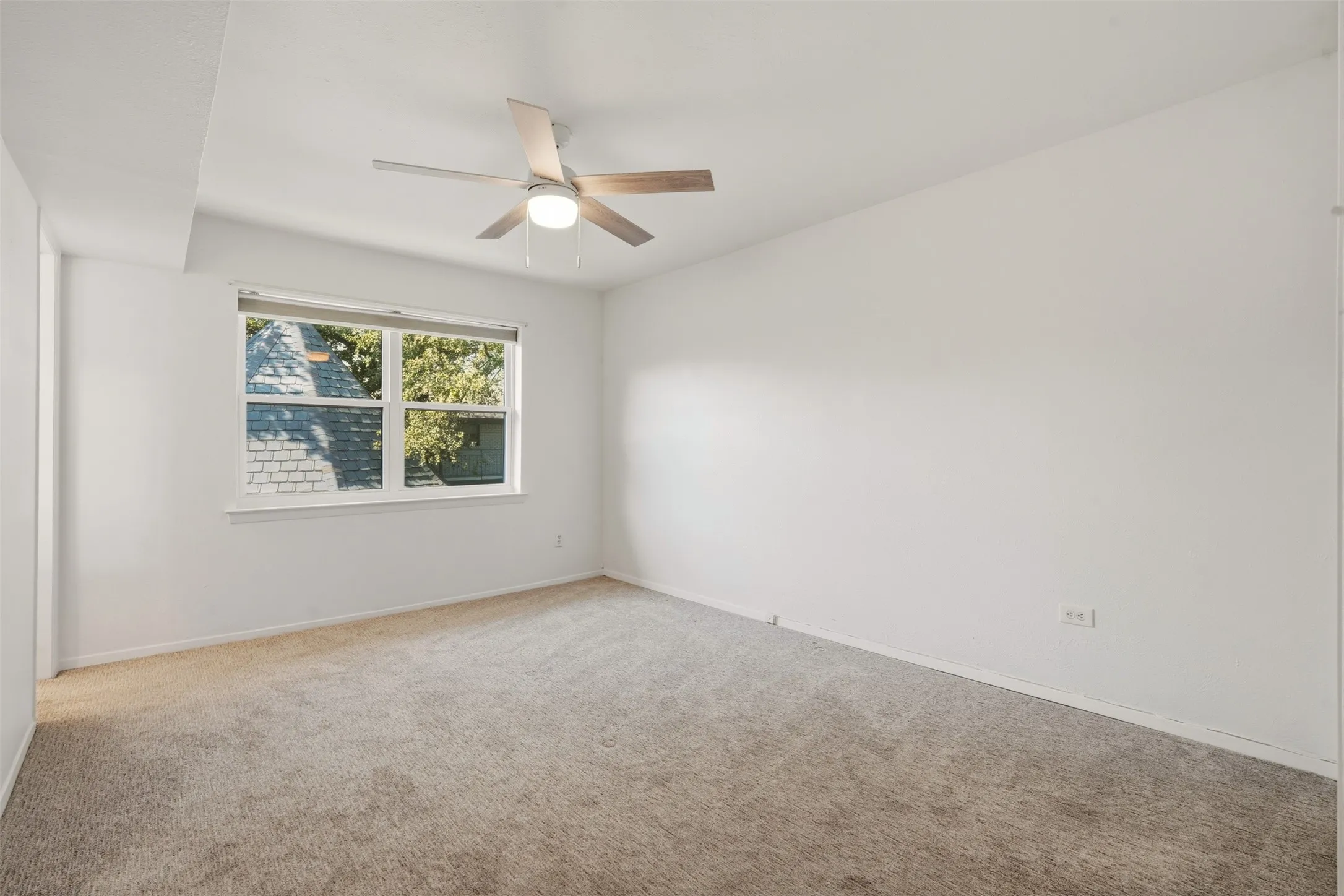 Carpeted flooring, white painted walls, white trim, window with roller shade, and a ceiling fan with integrated lighting