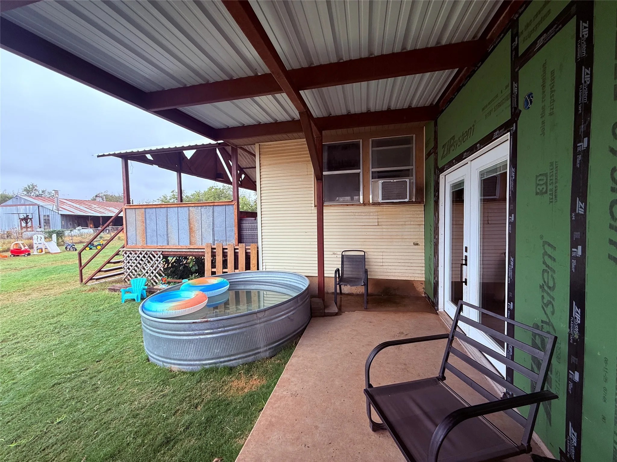 Covered patio with a corrugated metal roof and concrete flooring