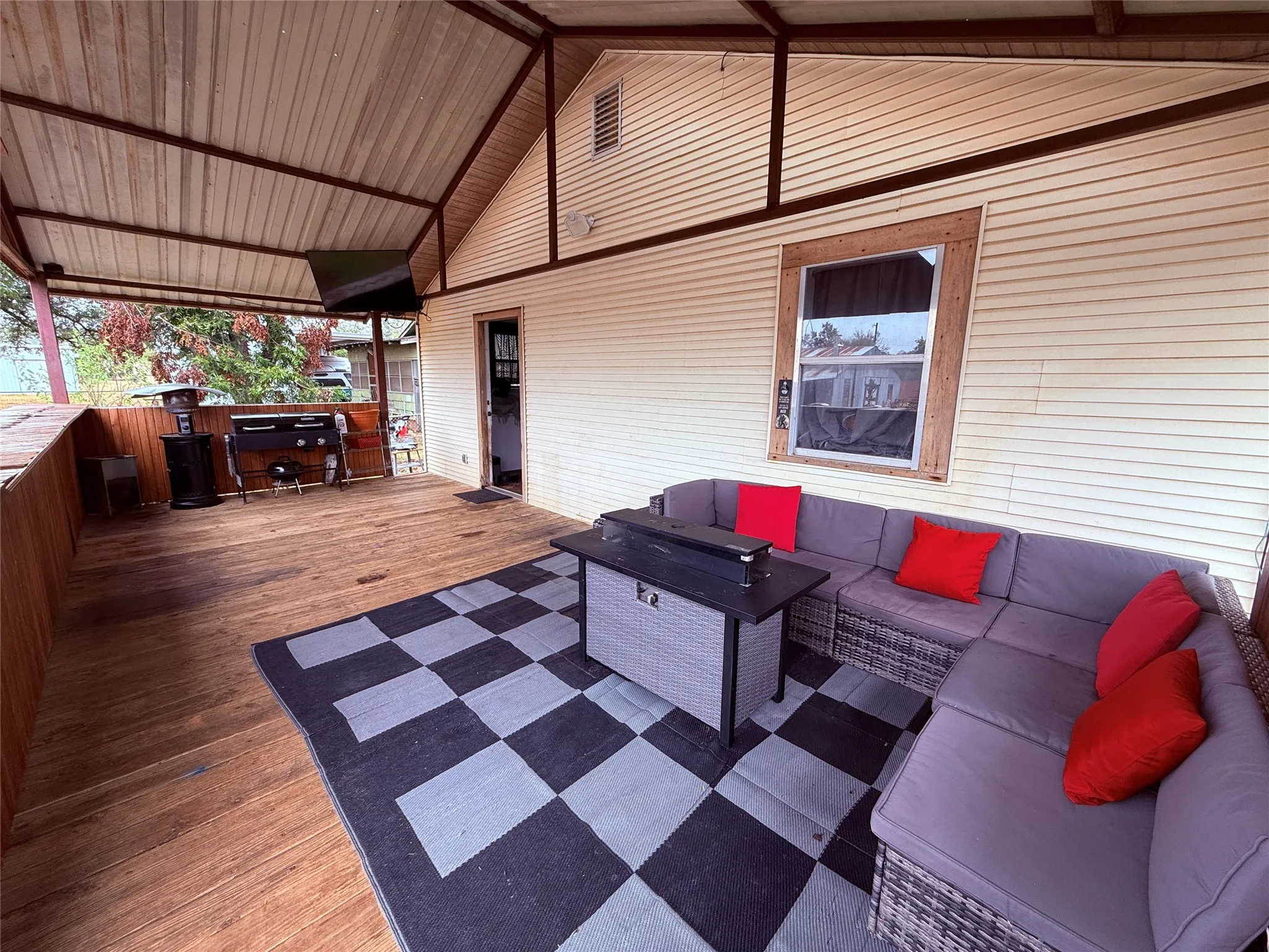 Covered outdoor living space featuring a wood deck, open gabled roof, and exterior siding
