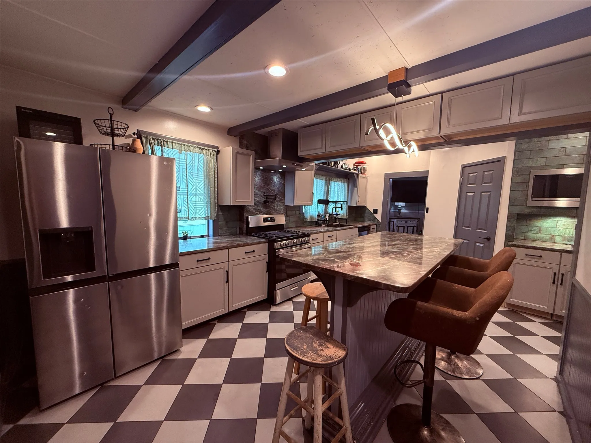Kitchen featuring checkerboard flooring, stainless steel appliances, an eat-at island with a stone-finish countertop, recessed lighting, and exposed ceiling beams