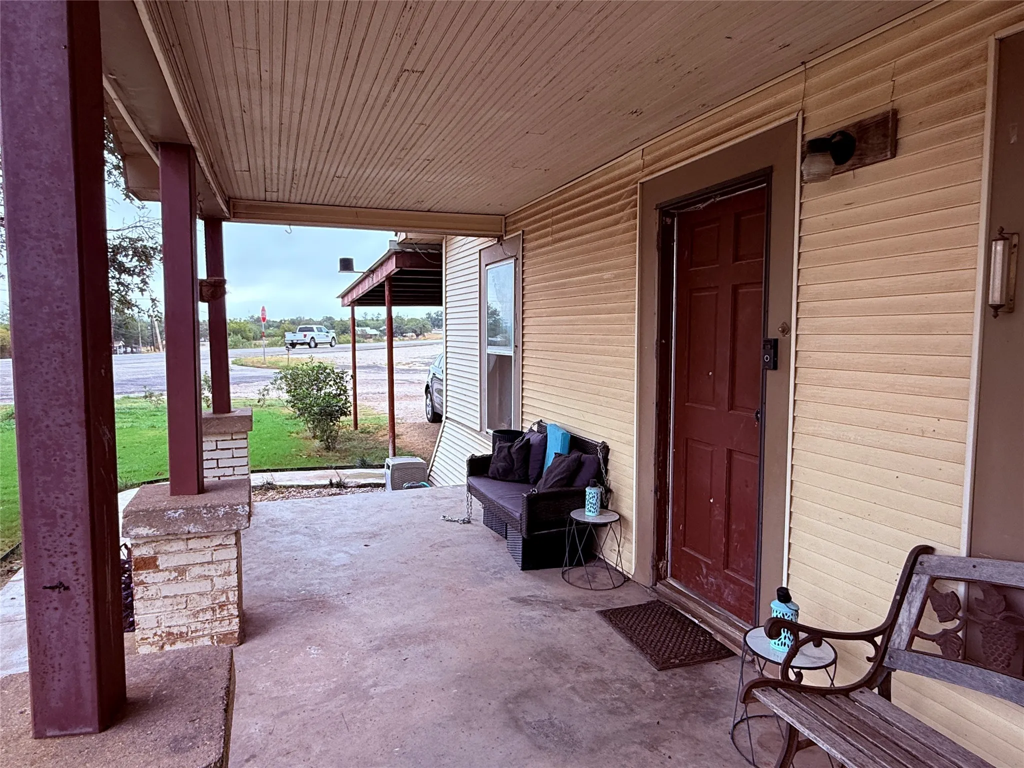 Covered front porch with concrete flooring and exposed ceiling beams