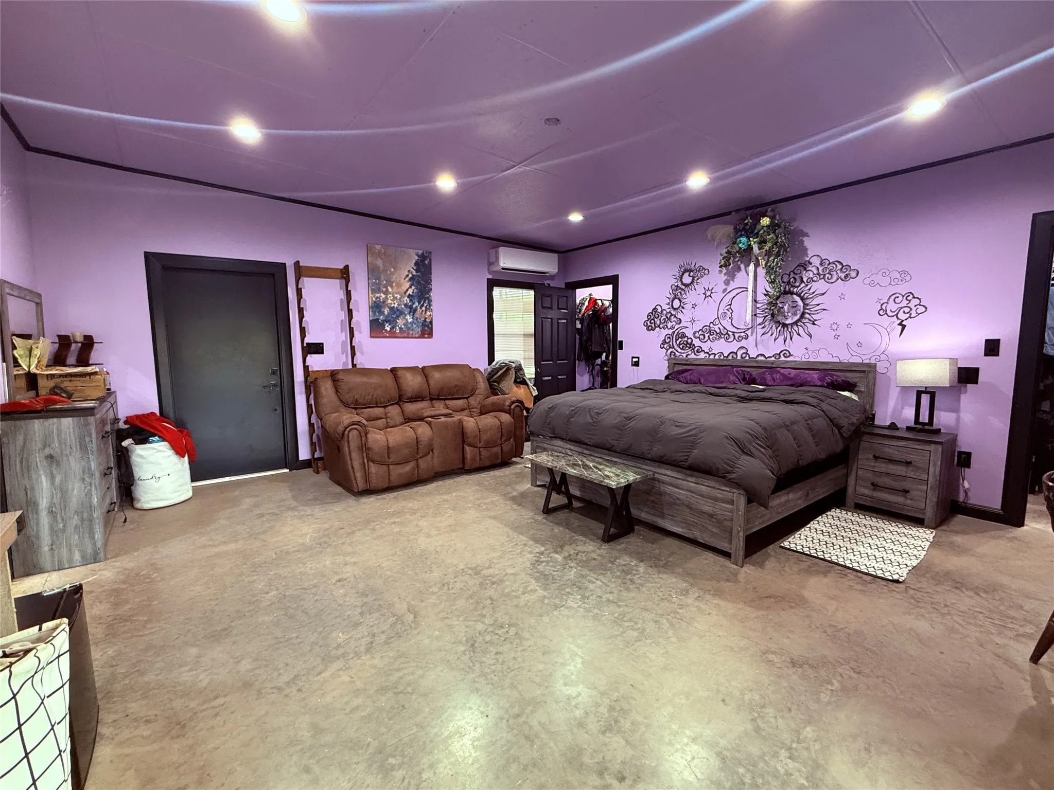 Painted walls with decorative wall art, recessed ceiling lights, and concrete flooring