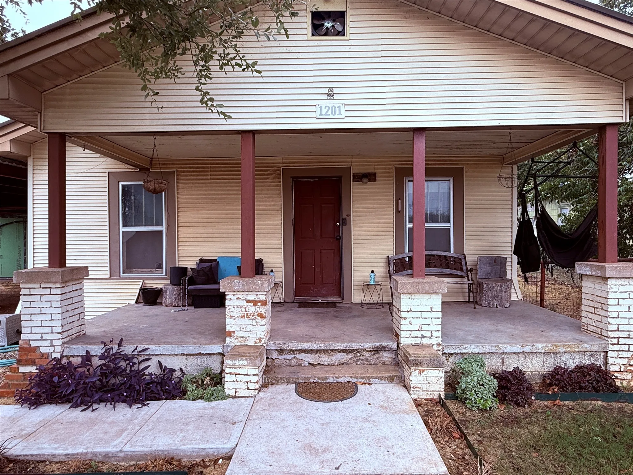 Front facade with horizontal siding, covered porch, and brick column bases