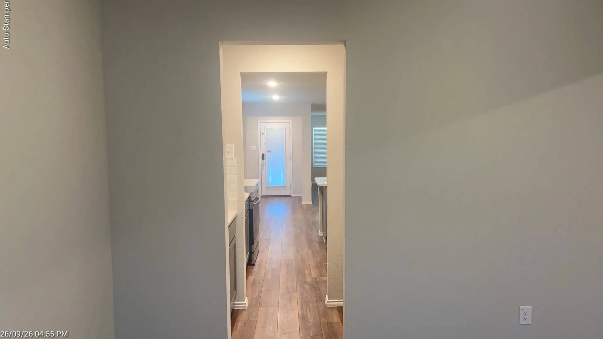Wood-finish flooring leading to a kitchen with white subway tile backsplash, recessed lighting, and stainless steel appliances