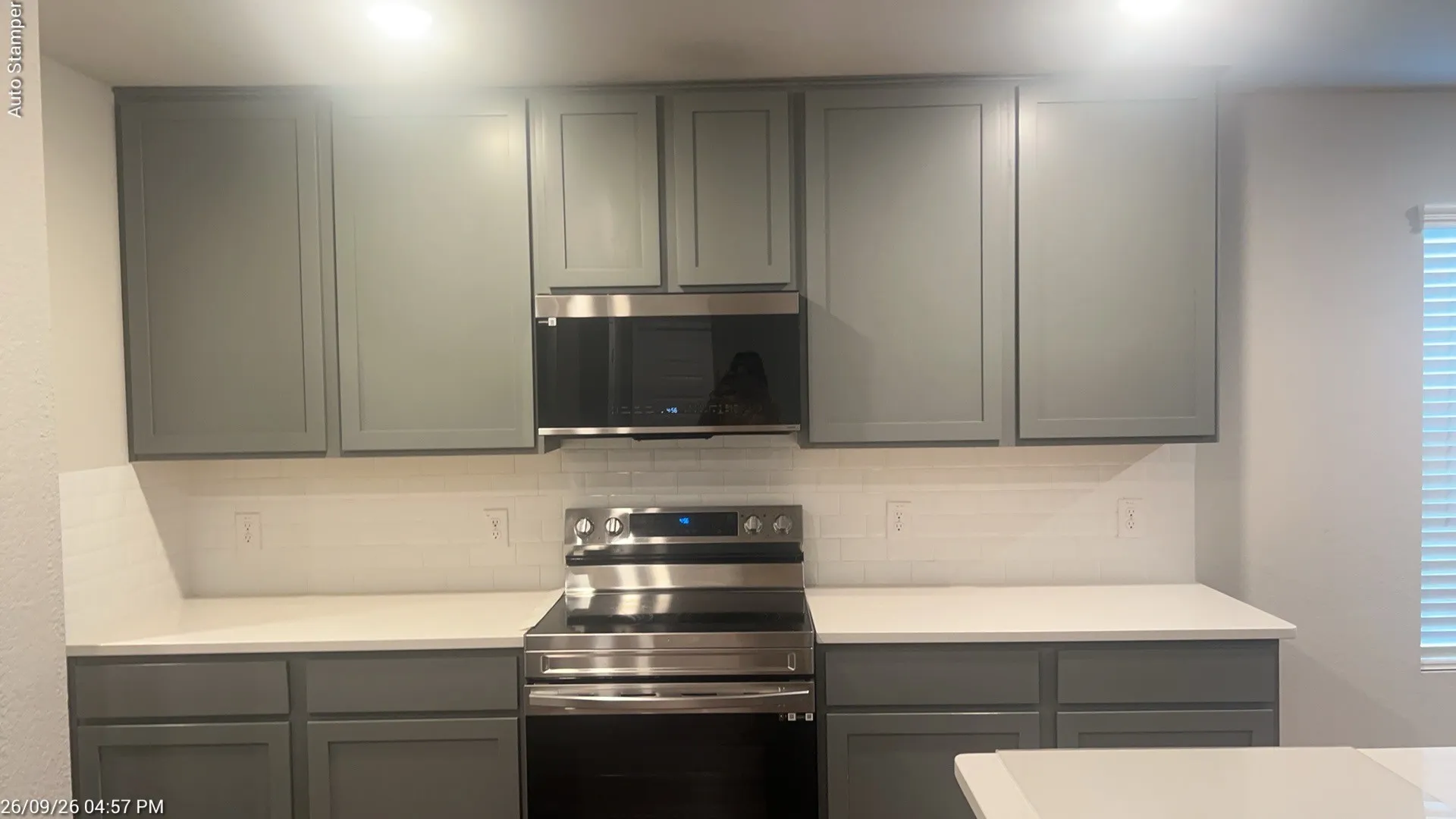 Gray shaker-style cabinetry, white countertops, subway tile backsplash, and stainless steel appliances