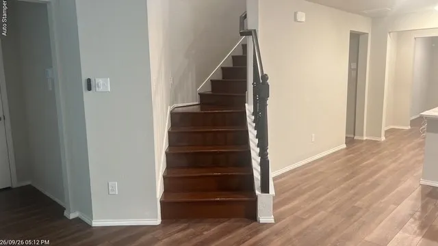 Wood-finish flooring throughout, staircase with dark wood treads, black newel post and balusters, and white risers and stringer