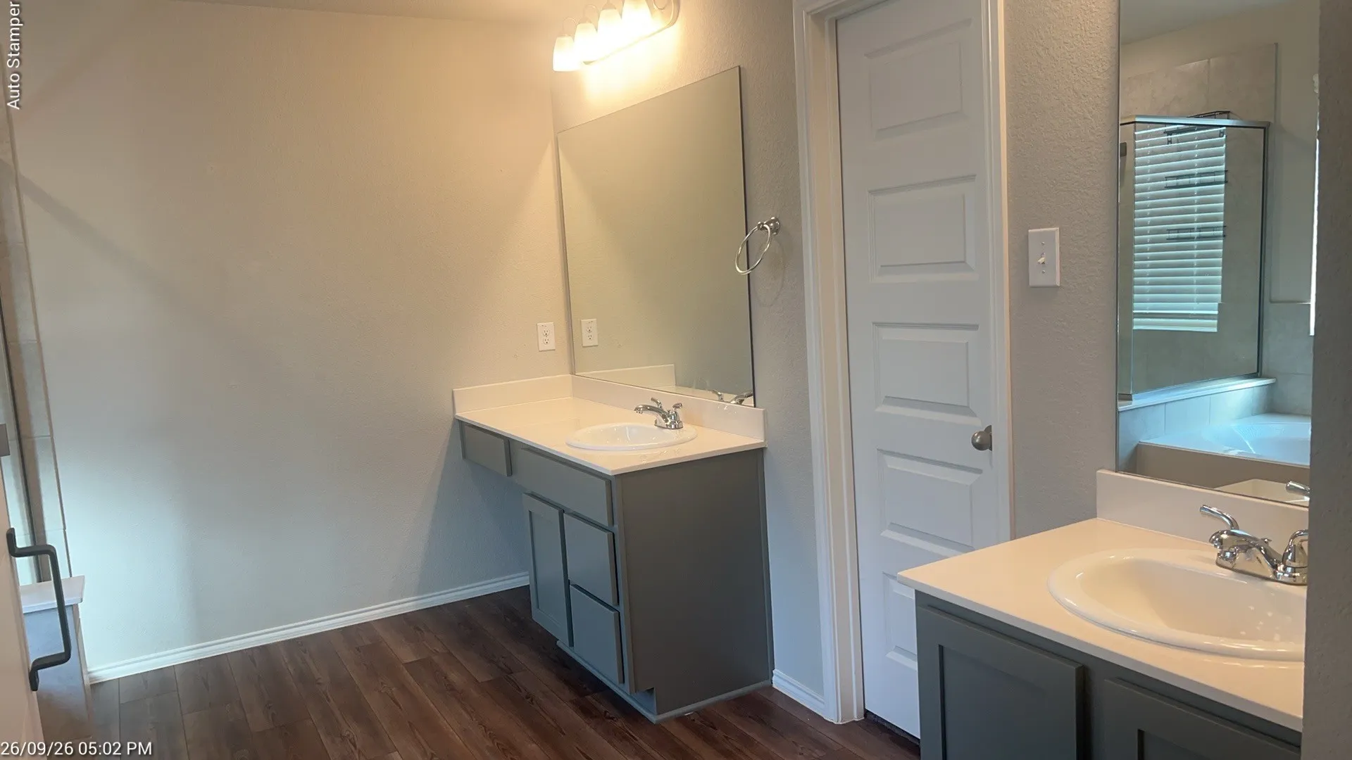 Dual vanities with integrated sinks, wood-finish flooring, and a built-in shower/tub combination