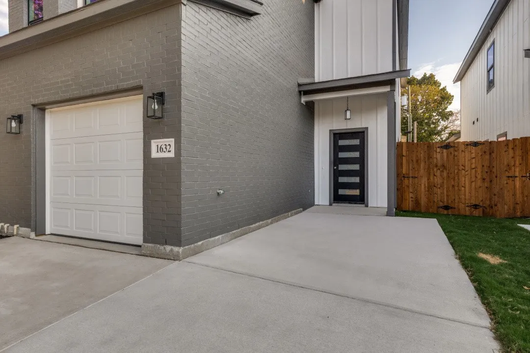 Contemporary exterior featuring painted brick, board and batten siding, a prominent wood fence, a two-car garage, and a modern front entry door
