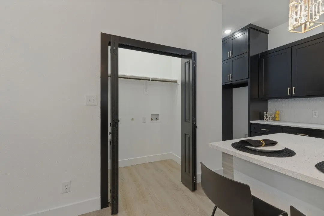Modern kitchen featuring dark cabinetry, white subway tile backsplash, and light-toned countertops