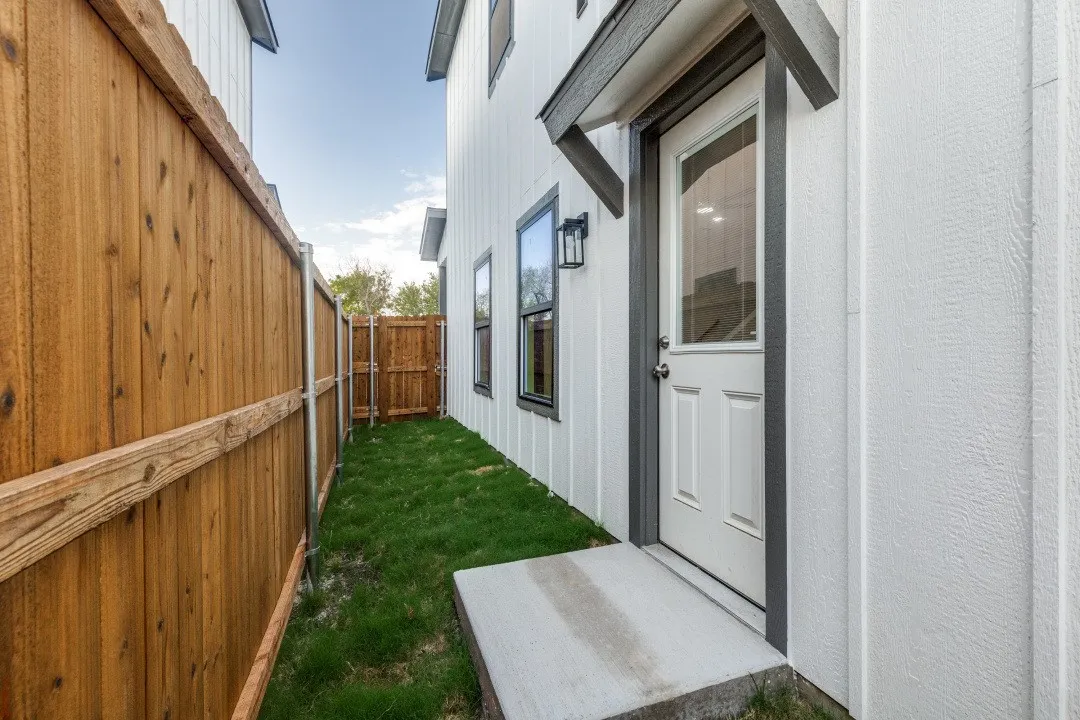 Concrete entry pad with a white paneled door, dark trim, and a decorative awning