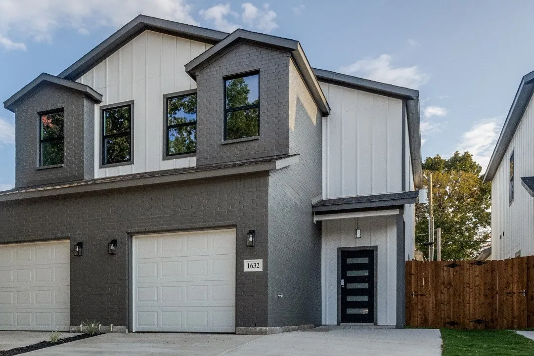 Modern exterior featuring a dark brick facade, white vertical siding, black-framed windows, a contemporary front door with horizontal lites, and an attached two-car garage