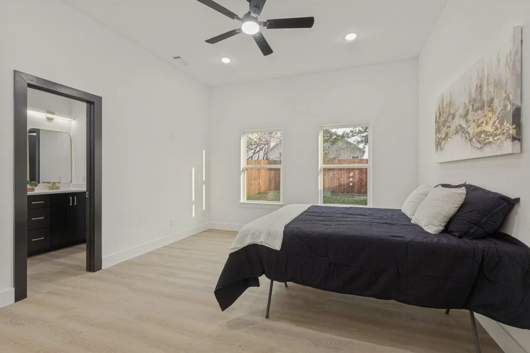 Recessed lighting, ceiling fan, two windows, wood-finish flooring, and a dark wood door frame